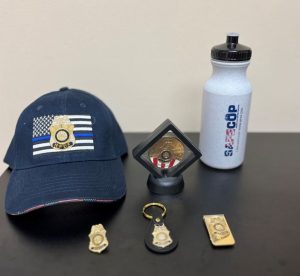 June 2024 Bundle NPDF Flag Hat, NPDF 25th Anniversary Challenge Coin in Display Case, Safe Cop Water Bottle, Wallet Badge Pin, NPDF Key Chain and Money Clip Image